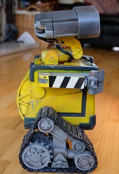 a yellow and black robot sitting on top of a wooden floor