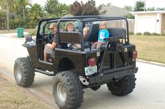 three children are riding in the back of a jeep