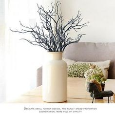 there is a vase with some branches in it on the table next to a couch