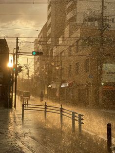 a city street is flooded with water as the sun goes down and people are walking in the rain