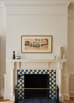 a living room with a fireplace and pictures on the wall above it's mantle