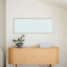 a plant is sitting on top of a wooden table in front of a white wall