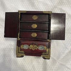 an old wooden chest with three drawers and brass hardware on the bottom, sitting on a white sheet