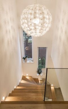 an overhead view of a stair case with lights on the bottom and below it is a circular chandelier that hangs from the ceiling