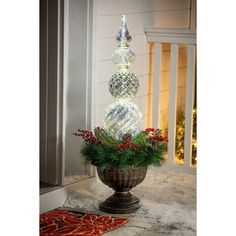 an outdoor christmas decoration with balls and greenery in a urn on the front porch