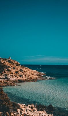 the water is crystal blue and there are rocks on the shore