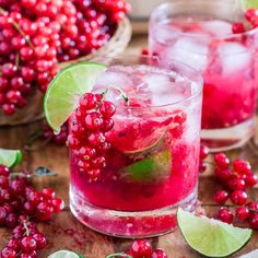 two glasses filled with liquid and garnished with limes on a wooden table