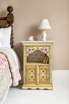 a bed room with a neatly made bed and a small cabinet on the floor next to it