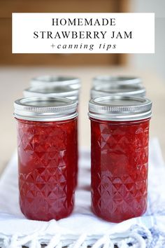 two jars filled with homemade strawberry jam sitting on top of a table