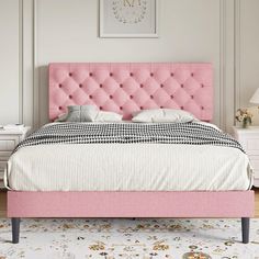 a bed with pink headboard and foot board in a white room next to a rug