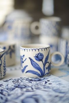 two blue and white cups sitting on top of a table next to each other,