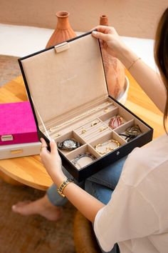 a woman holding an open box with jewelry inside