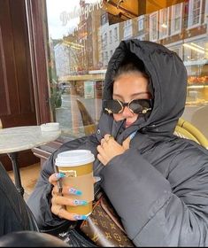 a woman sitting on a bench holding a cup of coffee