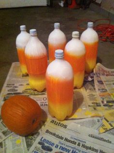 six orange and white plastic bottles sitting on top of newspaper next to an orange pumpkin