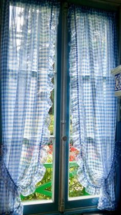 an open window with blue and white checkered curtains