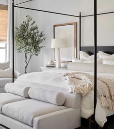 a bed with white sheets and pillows in a bedroom