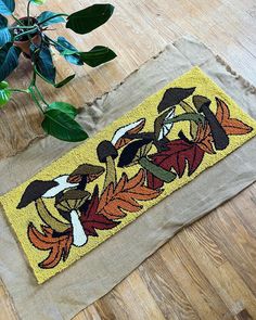 a yellow door mat sitting on top of a wooden floor next to a potted plant