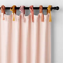 pink curtains with yellow tassels hanging from the top and bottom, in front of a white wall