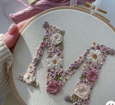 a hand embroidered letter with flowers on it