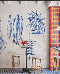 an artisticly painted wall in a restaurant with stools and tables, along with fish on the wall