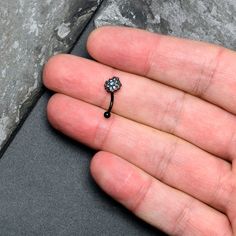 a person's hand holding a tiny flower shaped ring