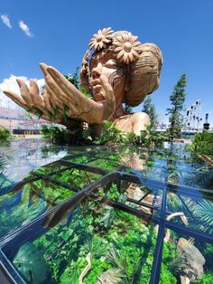 a large wooden statue sitting in the middle of a lush green forest filled with plants