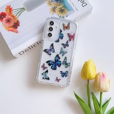 a phone case with butterflies on it next to tulips