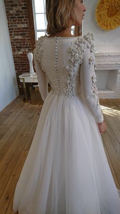 a woman in a white dress standing on a wooden floor with her back to the camera