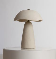 a white table lamp sitting on top of a white pedestal