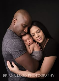 a man and woman holding a baby in their arms