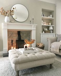 a living room filled with furniture and a fire place in front of a mirror on the wall