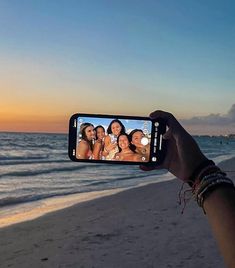 a person holding up a cell phone to take a picture of them on the beach