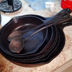 an old cast iron skillet with three spoons in it on a kitchen counter