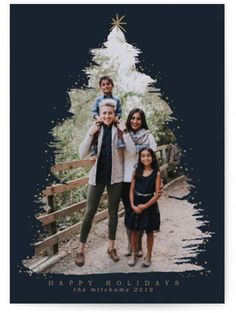 a family standing in front of a christmas tree with the words happy holidays written on it