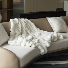 a large white blanket sitting on top of a couch next to pillows and a table