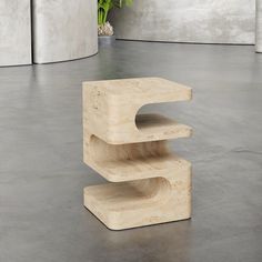 a white sculpture sitting on top of a cement floor next to a potted plant