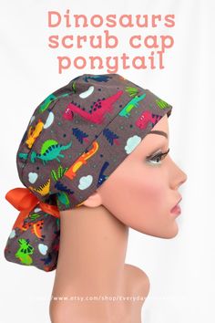 a woman's head wearing a scrub cap with dinosaurs on it and an orange bow