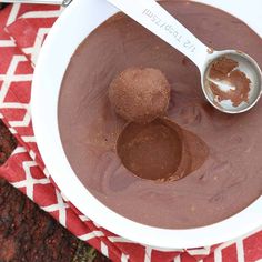 a white bowl filled with chocolate pudding and two spoons