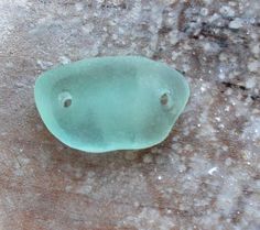 a close up of a green object on the ground with snow around it and water droplets