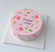 a pink birthday cake decorated with flowers and the words happy day on it's side