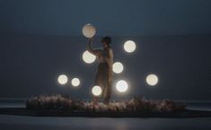 a woman standing on top of a grass covered field holding two white frisbees