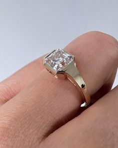 a woman's hand with a diamond ring on top of her finger, showing the center stone