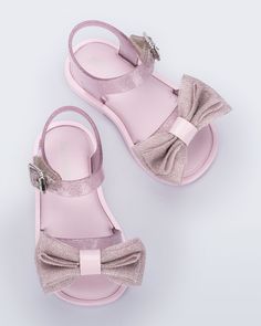 In this new style, the Mini Melissa Mar Sandal Sweet is donned with a petite layered bow appliqué, a glitter finish in varying colors, and an adjustable buckle closure for a safe and secure fit. Match with your little or pick a color for her to call her own. Pink Bow Sandals With Synthetic Material, Pink Synthetic Sandals With Bow, Cute Pink Party Sandals, Pink Open Toe Sandals With Bow Straps, Pink Glitter Sandals For Summer, Pink Glitter Sandals For Spring, Adjustable Glitter Sandals For Party, Cute Bow Sandals With Round Toe, Cute Sandals With Bow And Round Toe