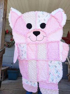 a person wearing a pink bear costume standing in front of a wooden structure with flowers on it