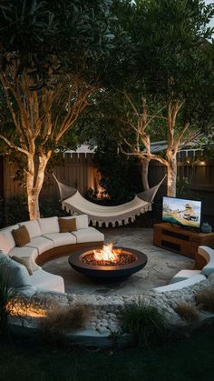 an outdoor fire pit surrounded by trees and hammock chairs at night with television in the background