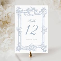 a table number card with white flowers in the background