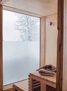 a wooden bench sitting next to a window in a room with snow on the ground