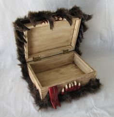 an open wooden box with fake teeth and claws on the inside, sitting on a white background