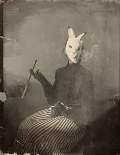 an old photo of a woman with a cat mask and holding a knife in her hand