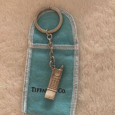 a cell phone keychain hanging from a blue case on a white carpeted surface